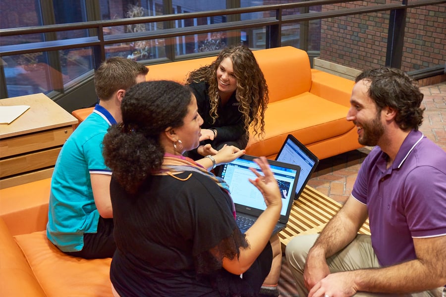 Group of Andersen employees sitting and talking on orange couches