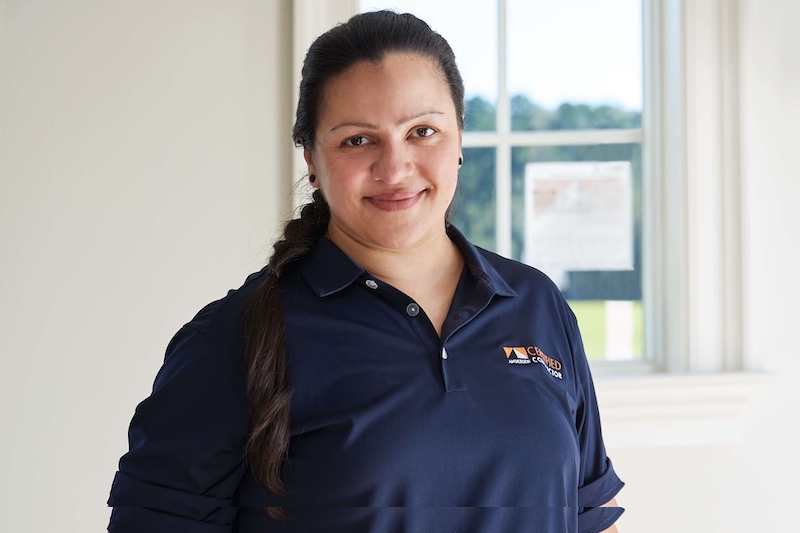 Female Certified Contractor standing by window with performance sticker on it