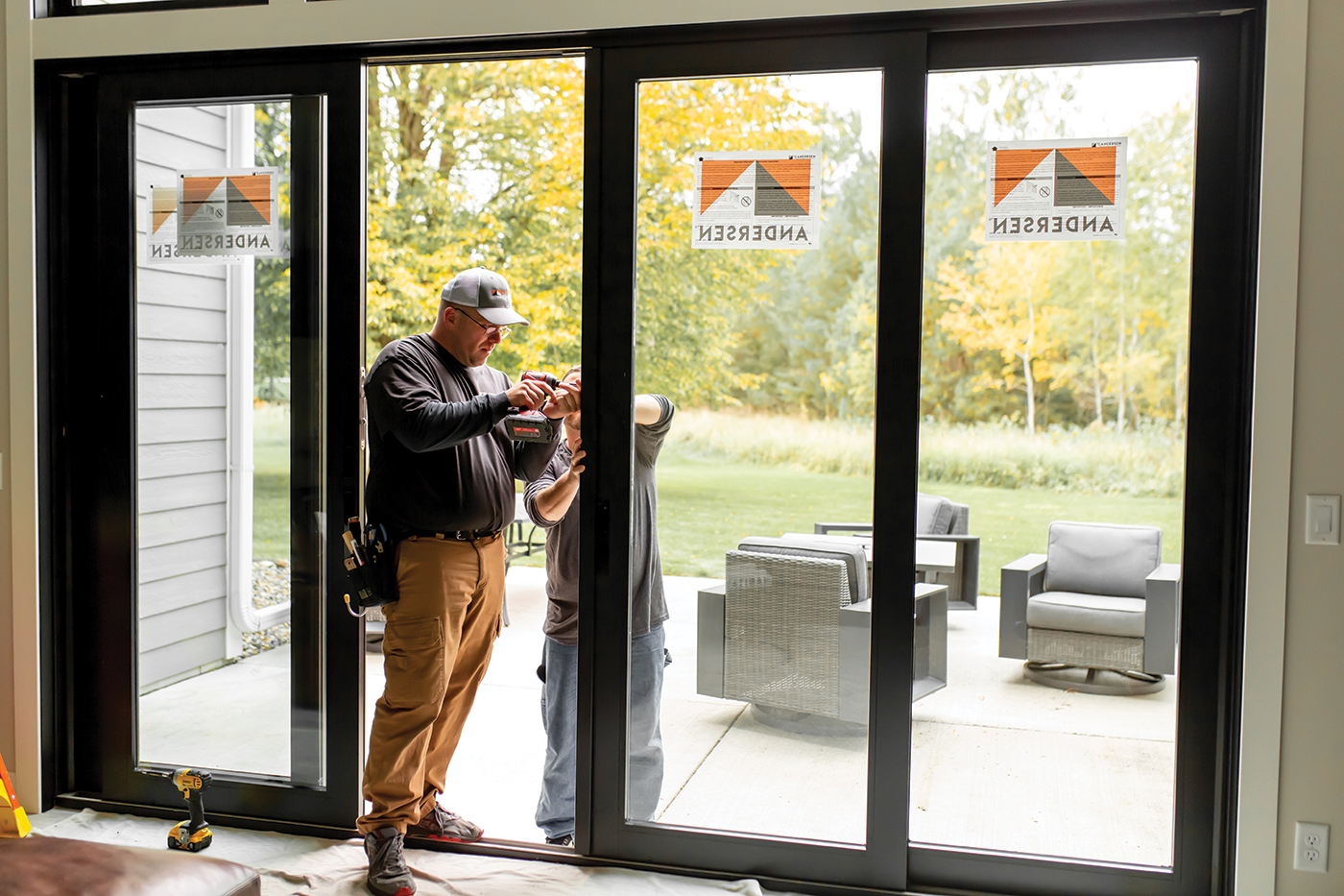 Two contractors install a four-panel Andersen A-Series Gliding Patio Door.