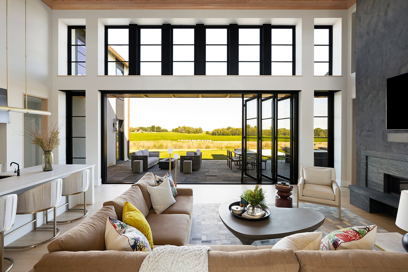 An open-concept living room and kitchen with a Folding Outswing Door connecting to a patio outside.