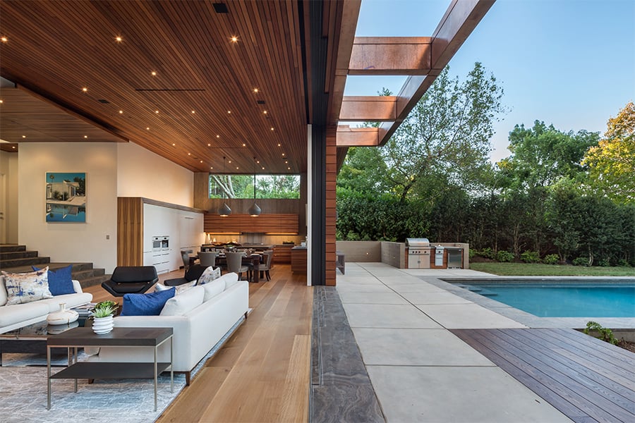 A woman sits outside a Pass-Through Window connecting a pool area with a kitchen.