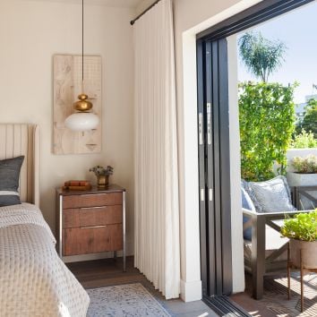 A bright bedroom with an open MultiGlide™ door leading to a patio area.