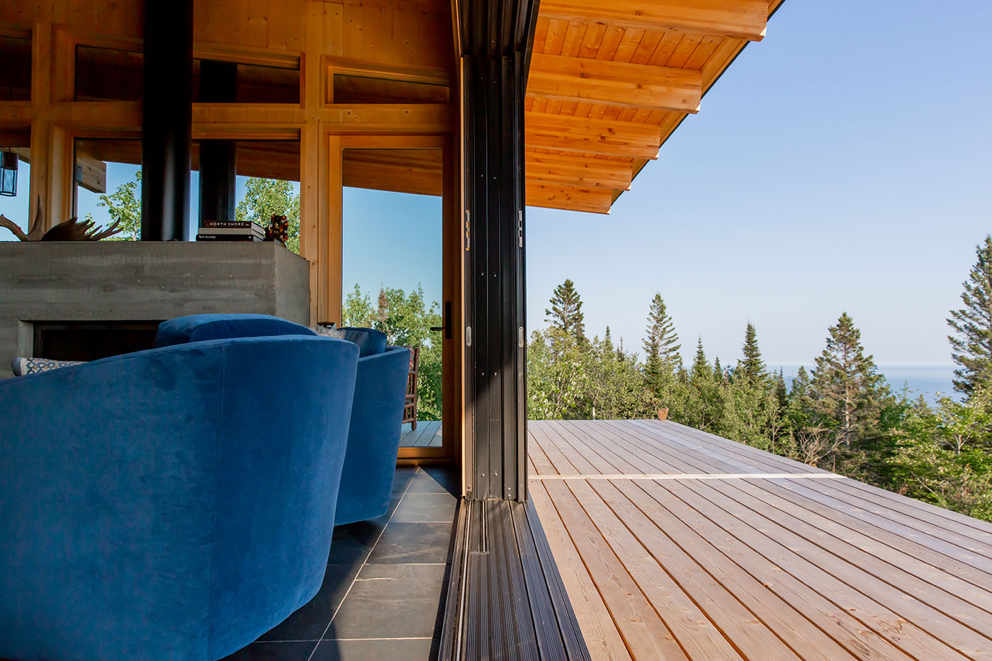 Image of a 6-panel MultiGlide Door fully pocketed in the wall, creating an open space between the living room and deck overlooking the outdoors of Grand Marais, Minnesota.