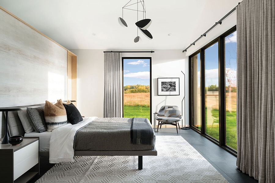A bedroom that blurs the line between indoors and outdoors due to the floor-to-ceiling windows