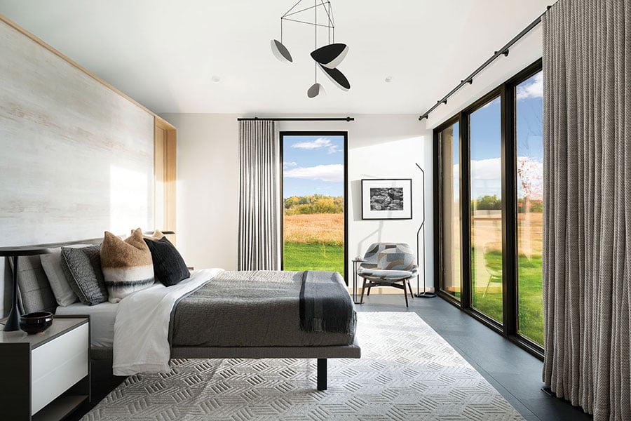 A bedroom that blurs the line between indoors and outdoors due to the floor-to-ceiling windows