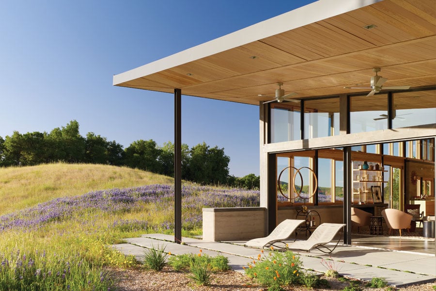A hilltop ranch home with a large overhang covering a patio that’s connected to the home through large Liftslide Doors.