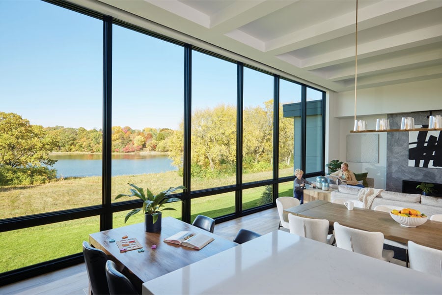 An open concept kitchen-living room with a wall of picture and awning windows facing the backyard.