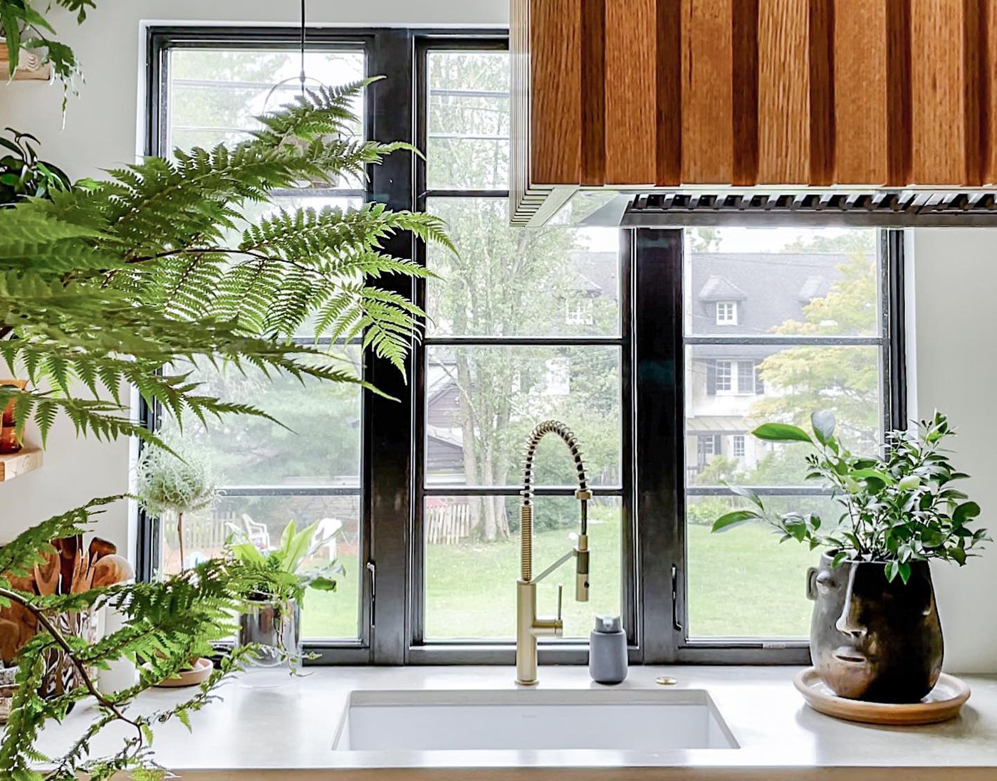 A kitchen sink with a row of three Andersen® E-Series Casement Windows behind it featuring a 4-over-1 specified equal light grille pattern.
