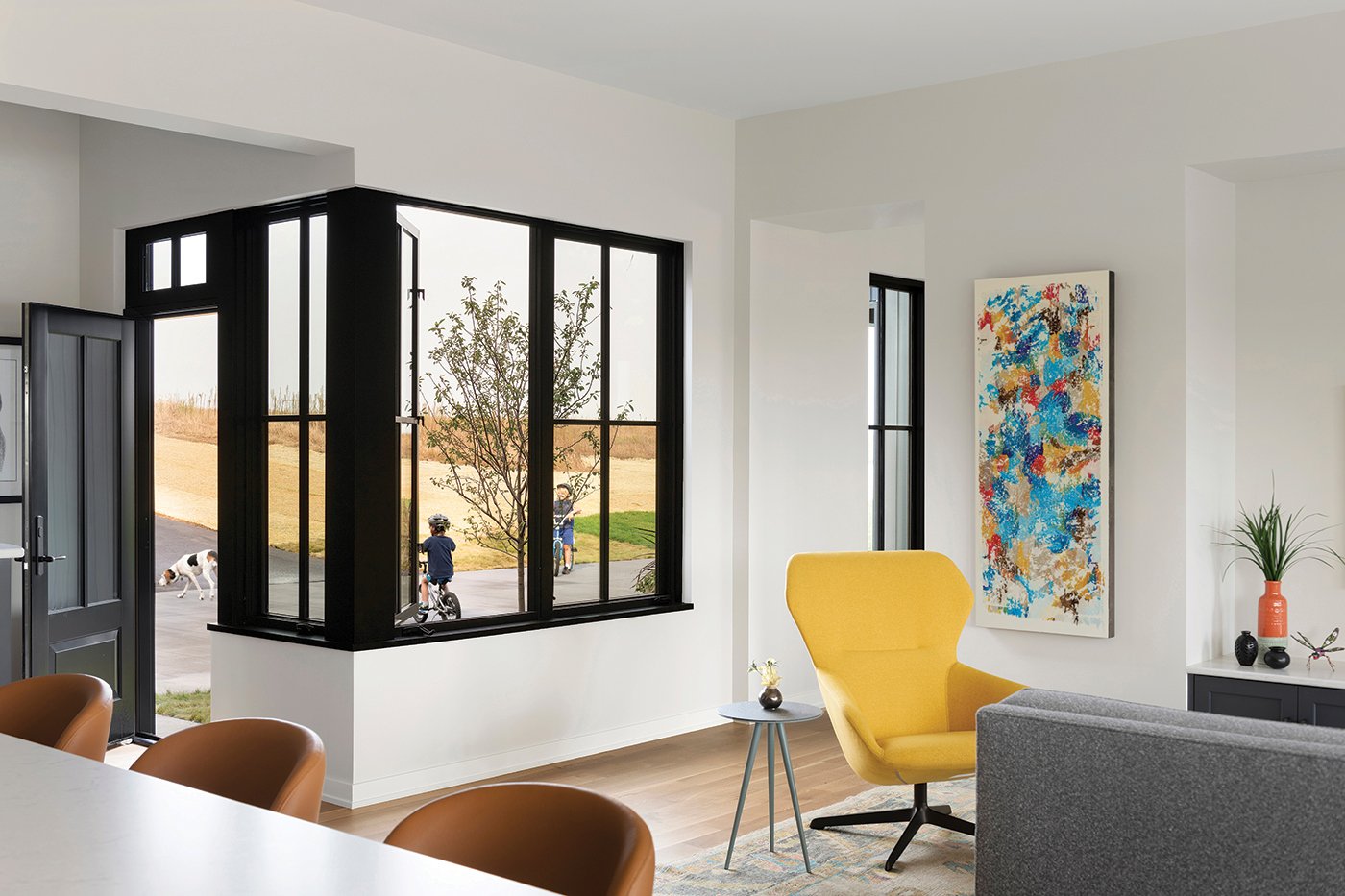 An open concept space that’s awash in light thanks to a corner window unit made of Andersen® E-Series Casement Windows with black frames and colonial grilles.