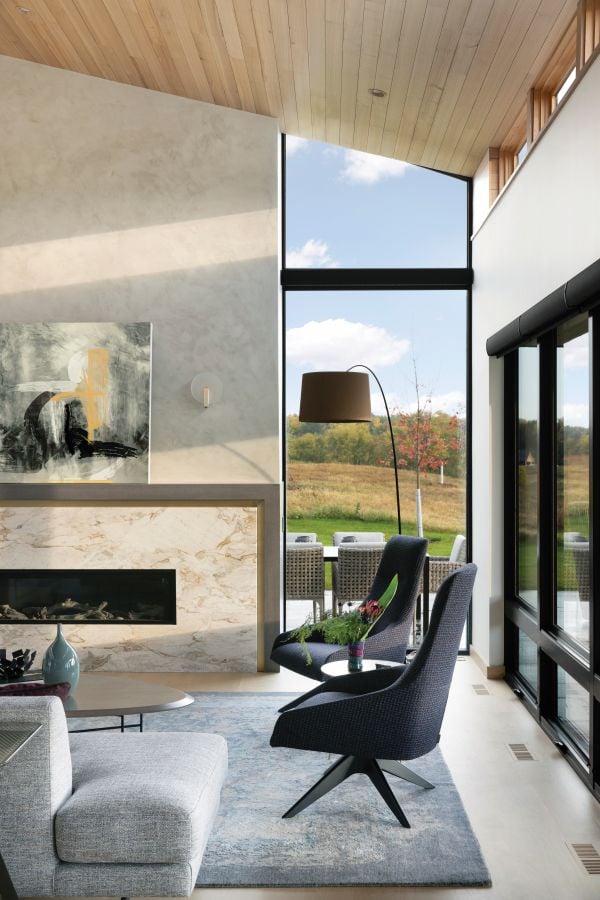 The living room of a modern home designed by Christopher Strom Architects features floor-to-ceiling windows.