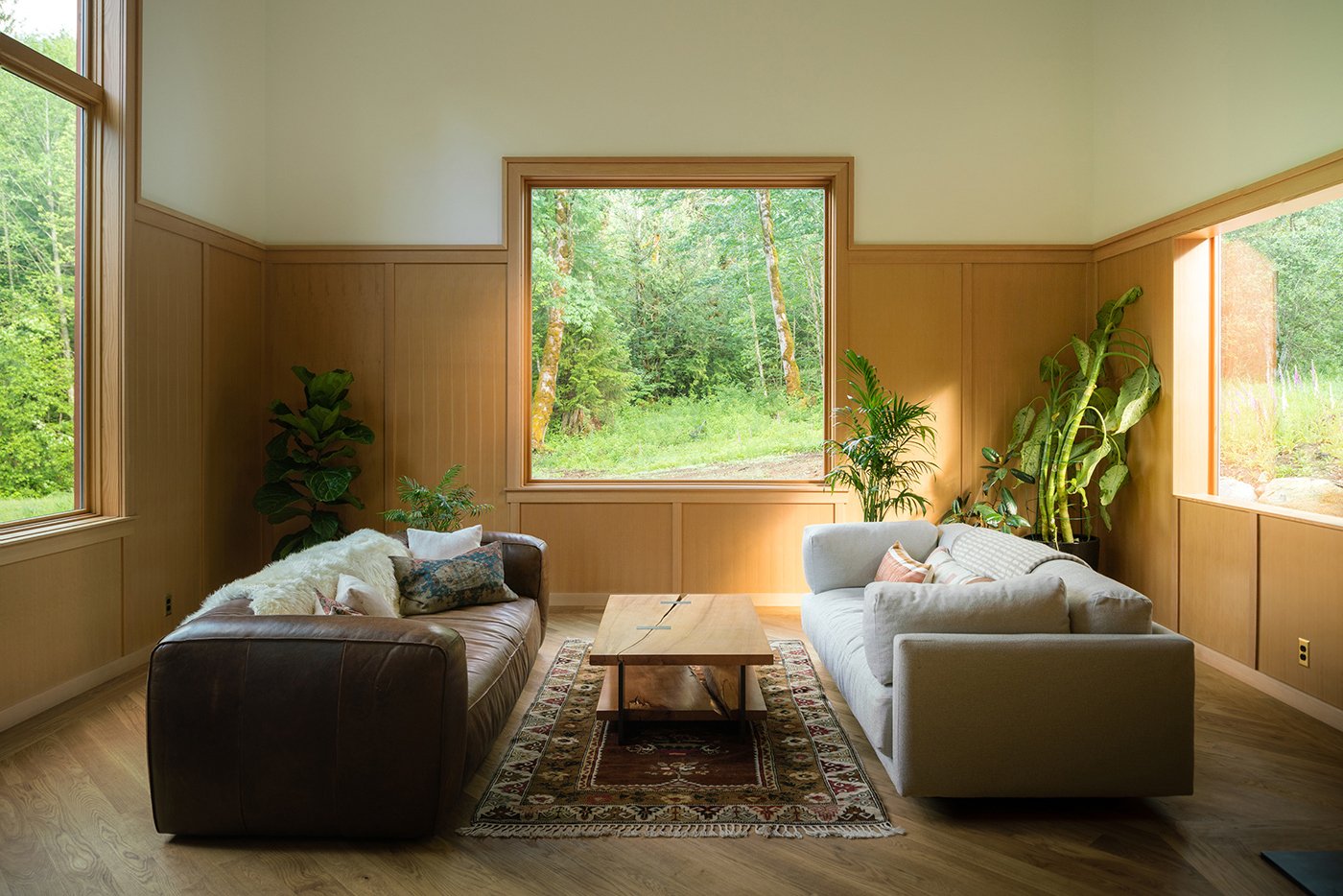 A living room with windows on three sides that are integrated into the wood paneling.