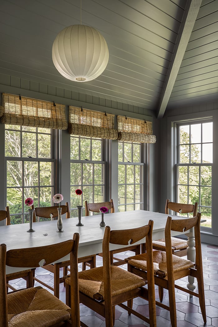 a porch with a monochrome blue color scheme, large windows and a dining table and chairs