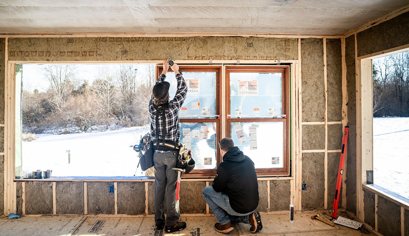 Two men installing windows in a framed out addition.