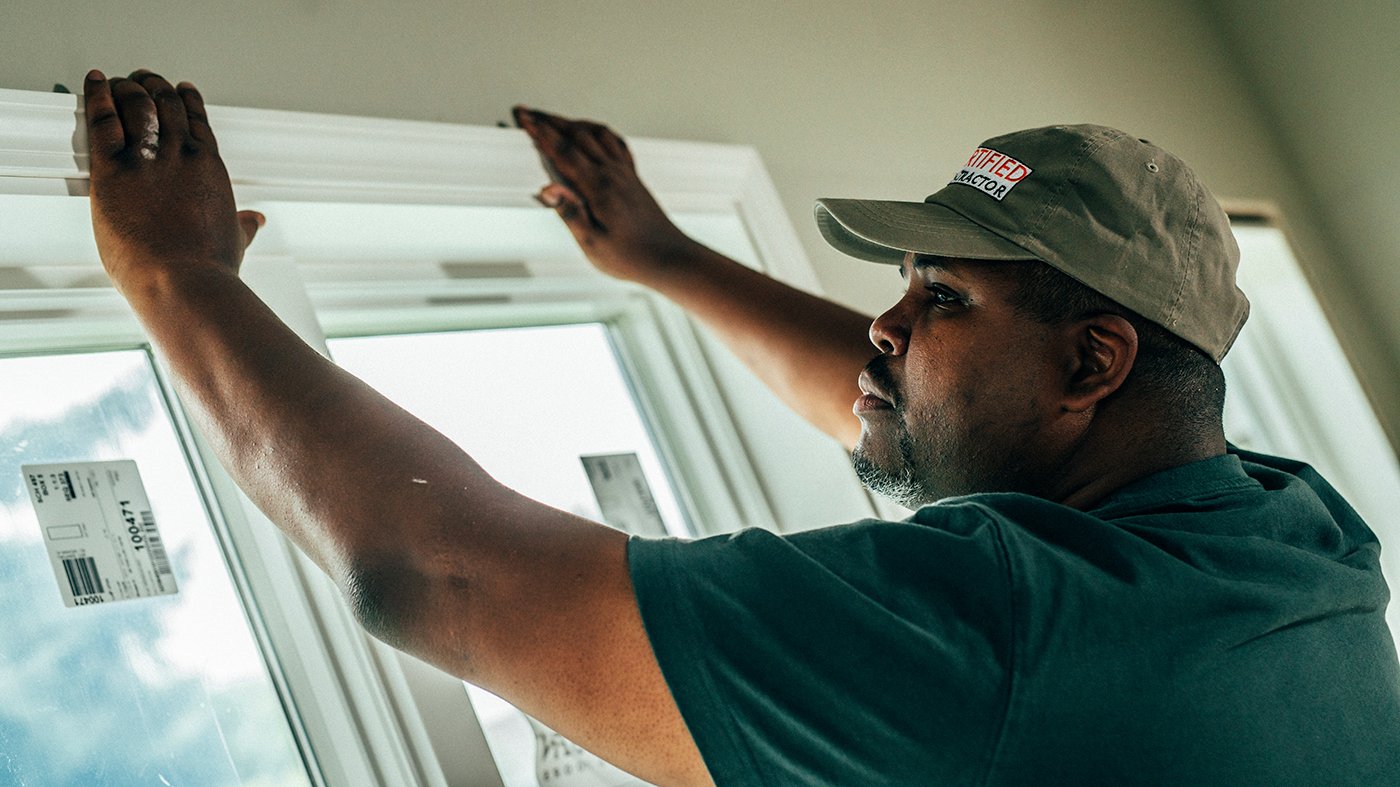A contractor installs trim around a new window.