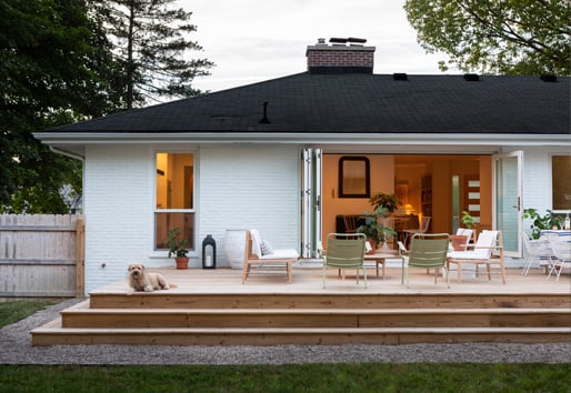 A white-painted Ranch home with an Andersen Folding Outswing Door opening to the deck outside.
