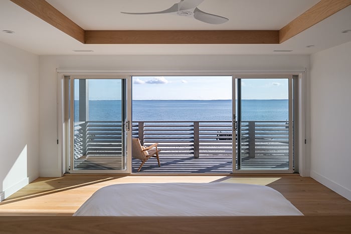 An open gliding patio door leading to a balcony with views of the water. 