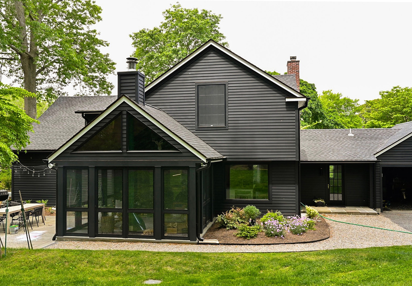 A black Cape Cod with a back porch that has triangular Andersen® 400 Series Flexiframe® Windows at the gable.
