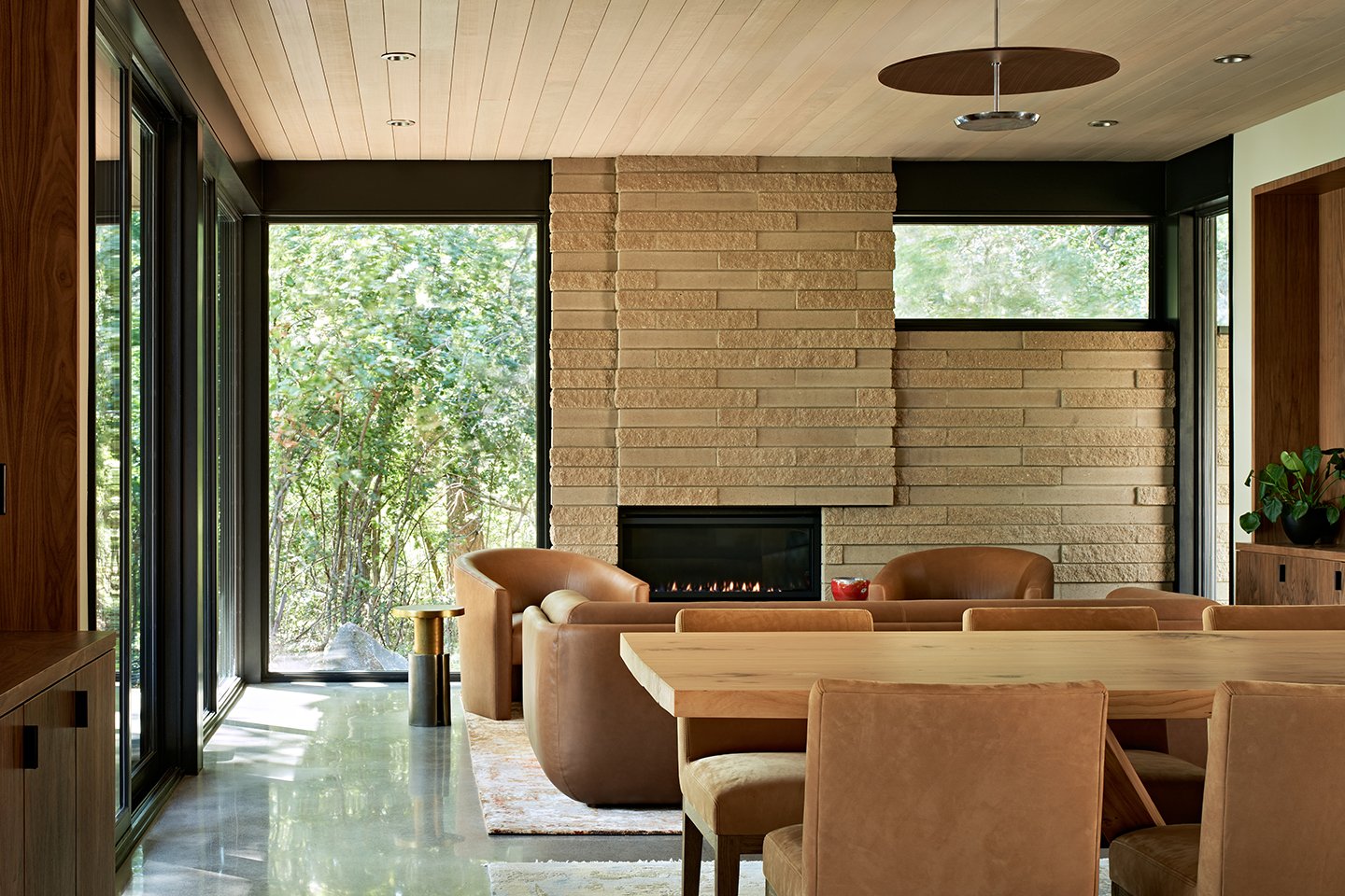 An open-concept dining and living room with floor-to-ceiling Andersen® E-Series Gliding Patio Doors and E-Series Picture Windows.