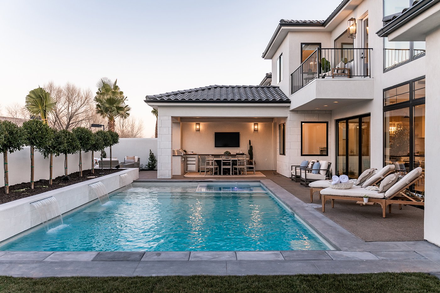 A contemporary luxury home in Utah with a pool, outdoor dining area, and large Andersen 100 Series black windows and an Andersen Aluminum Multi-Slide Door.