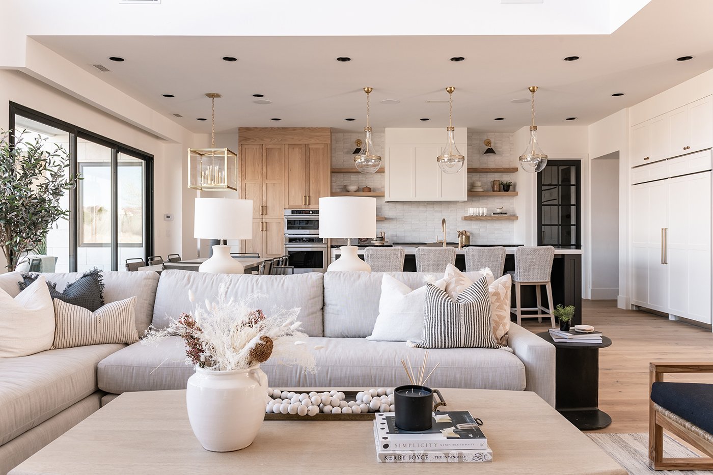 Kitchen and living room with a coastal contemporary look and feel with cool neutrals, natural wood, and modern black windows.  