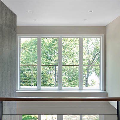 Interior of modern home with a balcony view through large, white Andersen Windows.