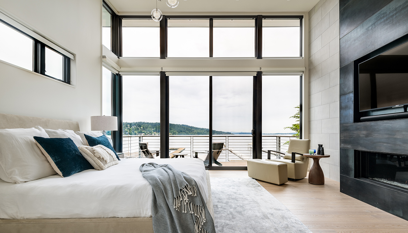 A bedroom with Andersen E-Series Gliding Doors flanked by stationary panels and topped with E-Series Picture Windows.