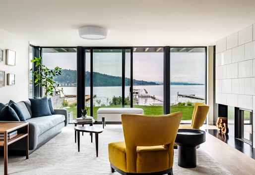 A living room with a wall of glass created by an Andersen® E-Series Gliding Patio Door flanked by stationary panels that wrap around a corner.