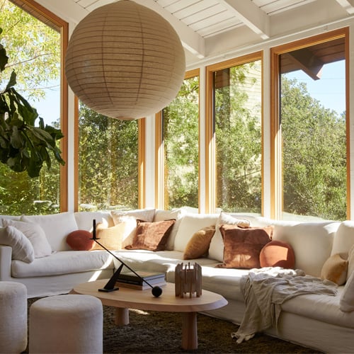 Cozy living area with warm wood frame windows leading to the nature in the backyard