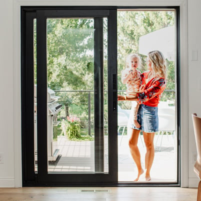 A kitchen connected to a deck by a black A-Series Gliding Patio Door with contemporary profiles.