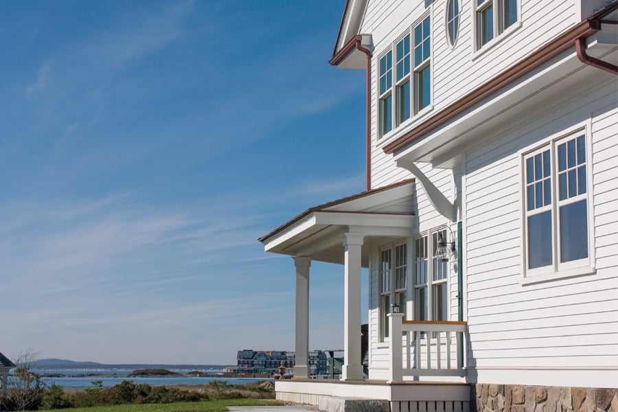 A classic white wood farmhouse on the coast with white 400 Series Double-Hung Windows.
