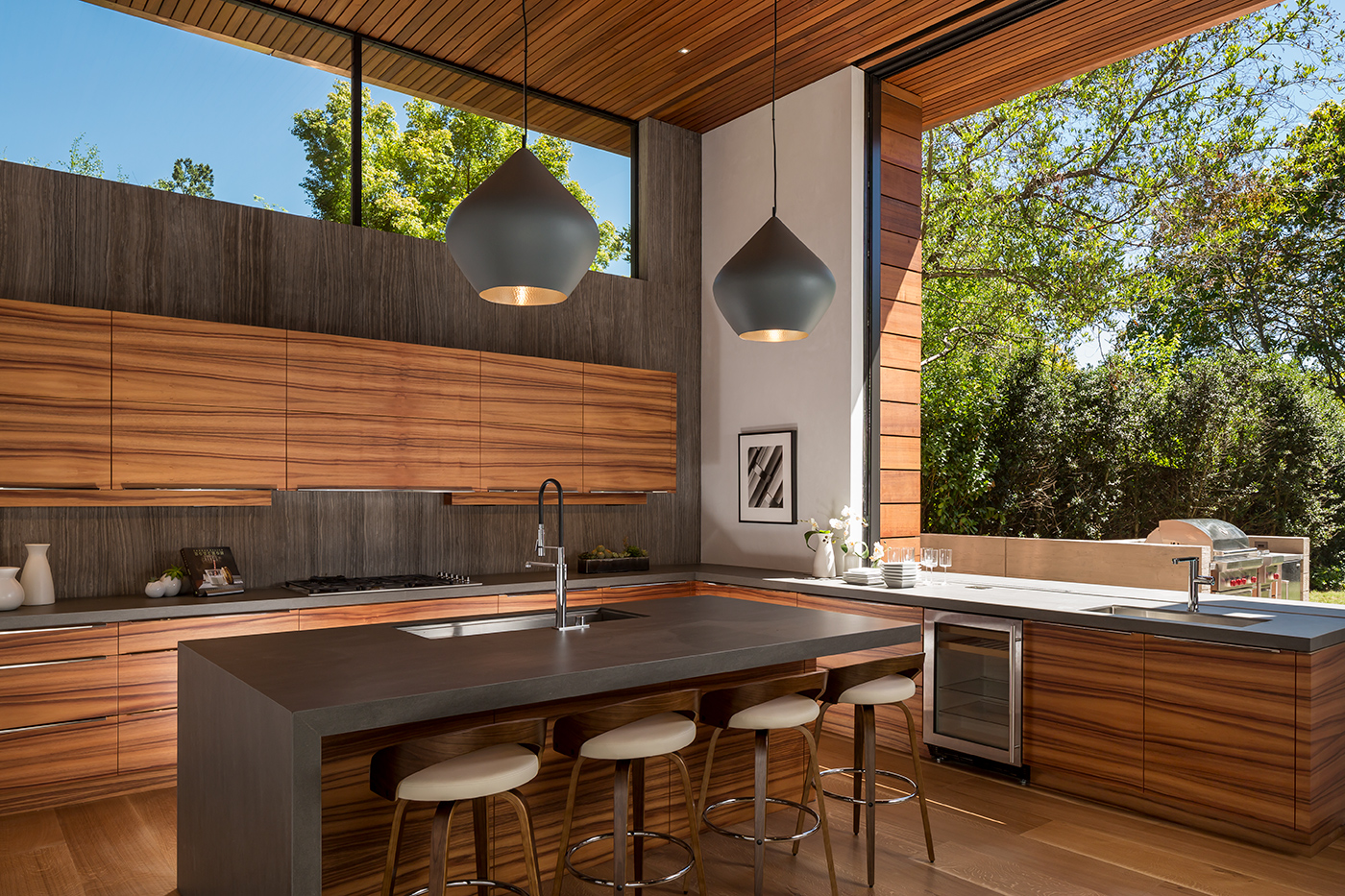 A monumental Andersen® Liftslide Pass-Through Window connects a kitchen with a patio.