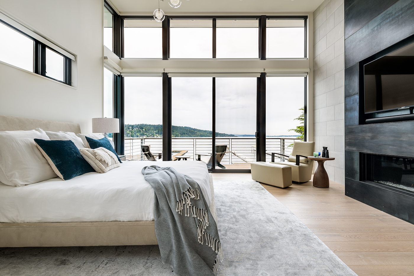 A bedroom with a full wall of glass created by an Andersen® E-Series Gliding Patio with windows attached on both sides and above.
