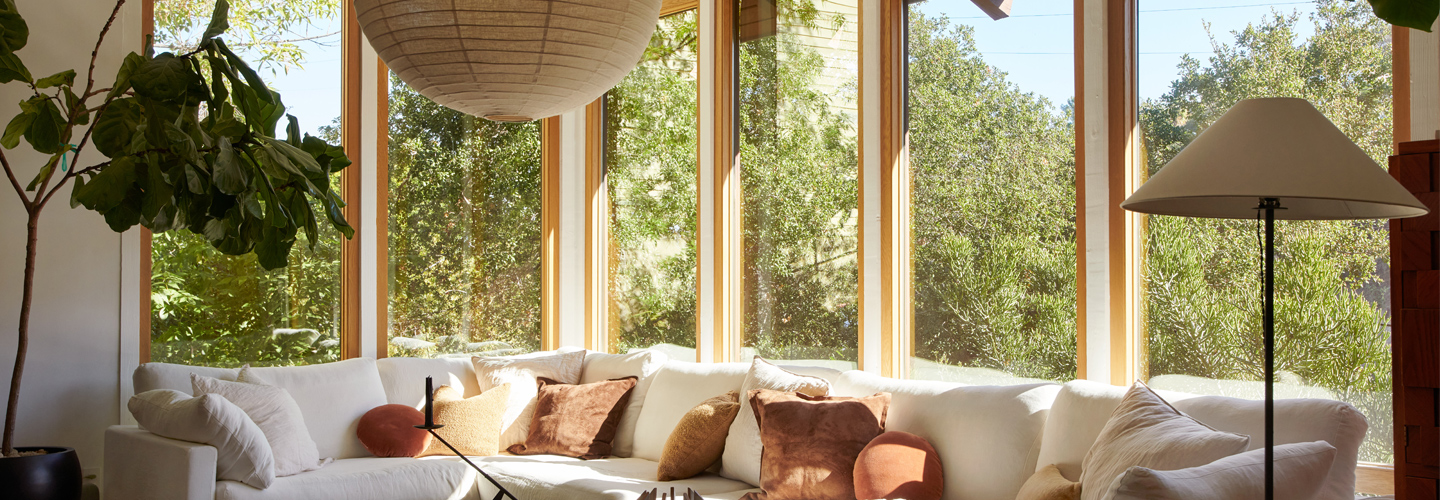 A dining room with floor-to-ceiling Andersen E-Series Windows with white oak frames that wrap around a corner.