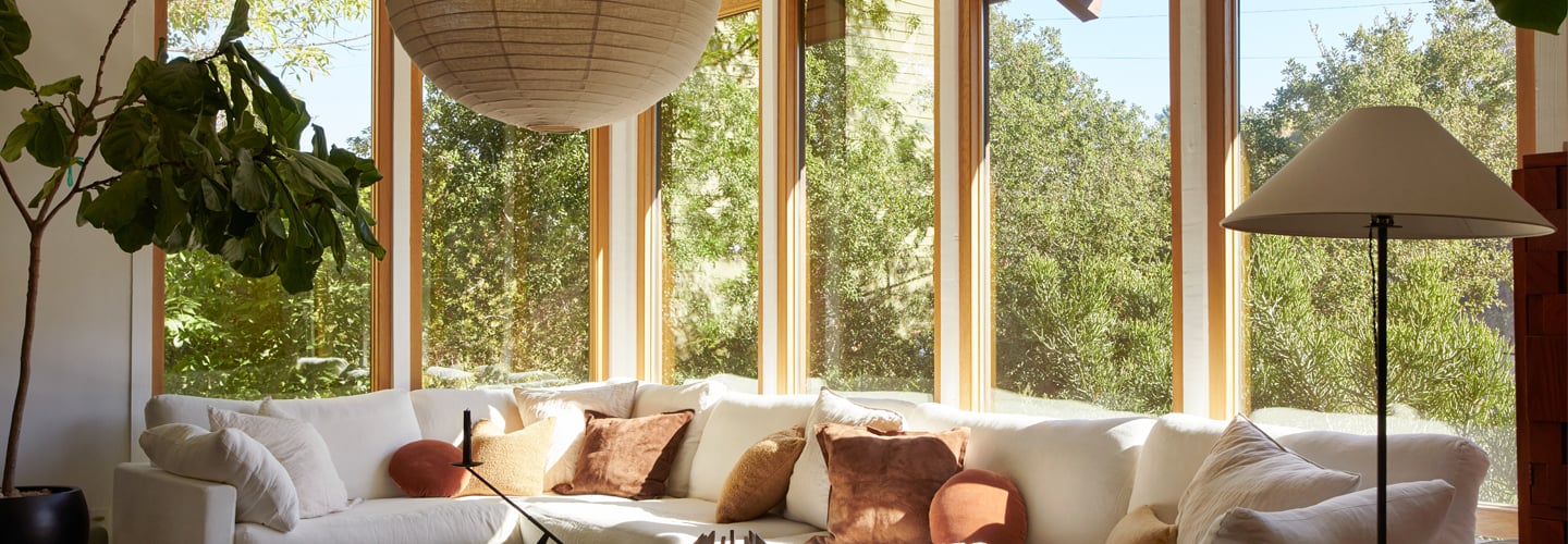 A dining room with floor-to-ceiling Andersen E-Series Windows with white oak frames that wrap around a corner.