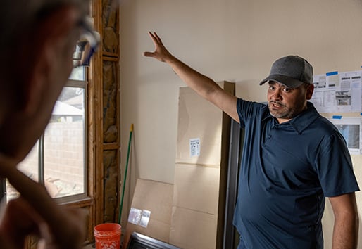 andersen contractor pointing at window replacement project inside house