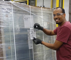 image of plant worker shrink wrapping andersen door