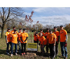A dozen orange-clad Andersen employee volunteers eagerly helped plant 65 trees at a park in the Minneapolis suburb of Brooklyn Park