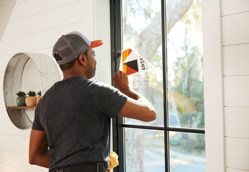 image of contractor removing andersen sticker from window
