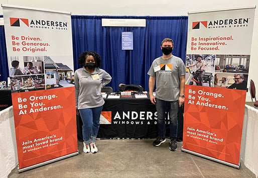 andersen employees at event standing by information table