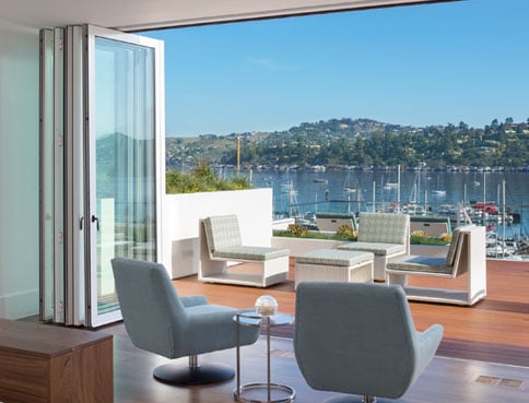 Bedroom with Andersen Windows beefy bifold doors open to a patio and beautiful ocean view.