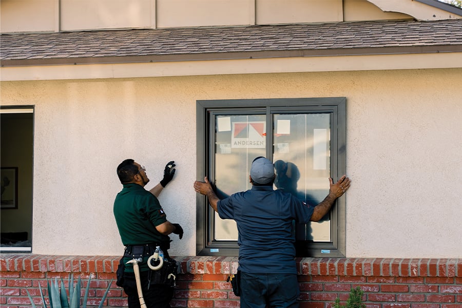 Two contractors install a flush fin window in a stucco home. 