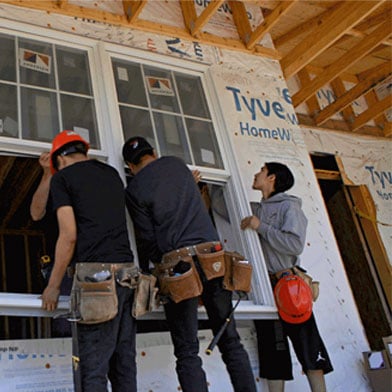 Young people putting in Andersen Windows on a home through the Building Construction Program.
