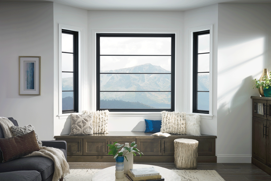 Three modern black-framed living room windows frame mountain views. 