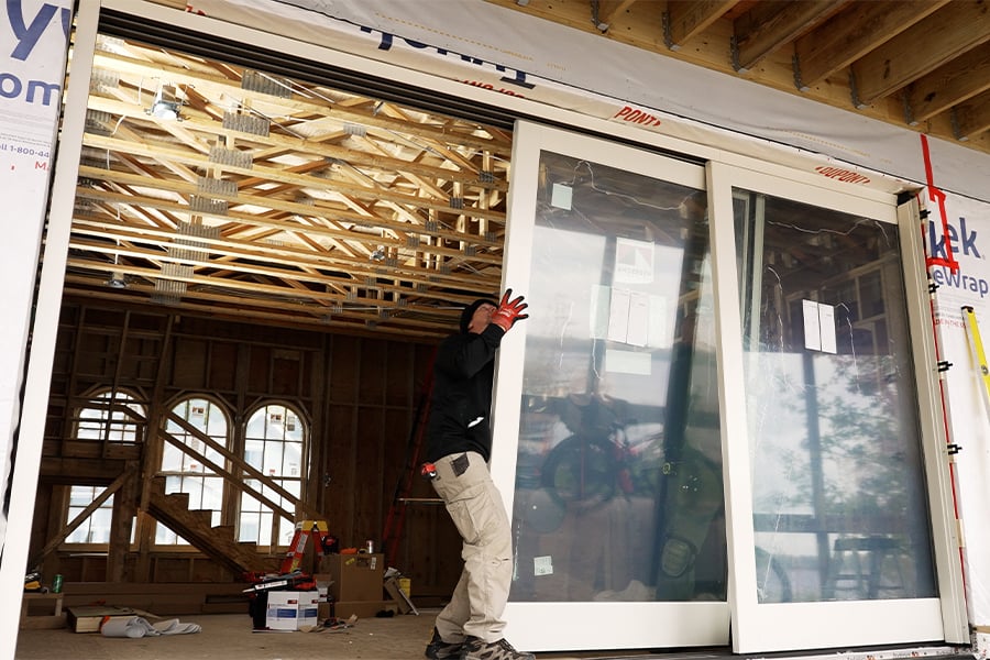 A man installs a MultiGlide door panel into a rough opening. 