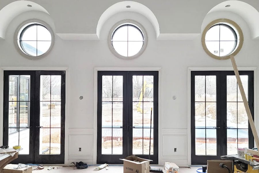 Three black-framed French doors with round windows above create a statement in a new construction home.