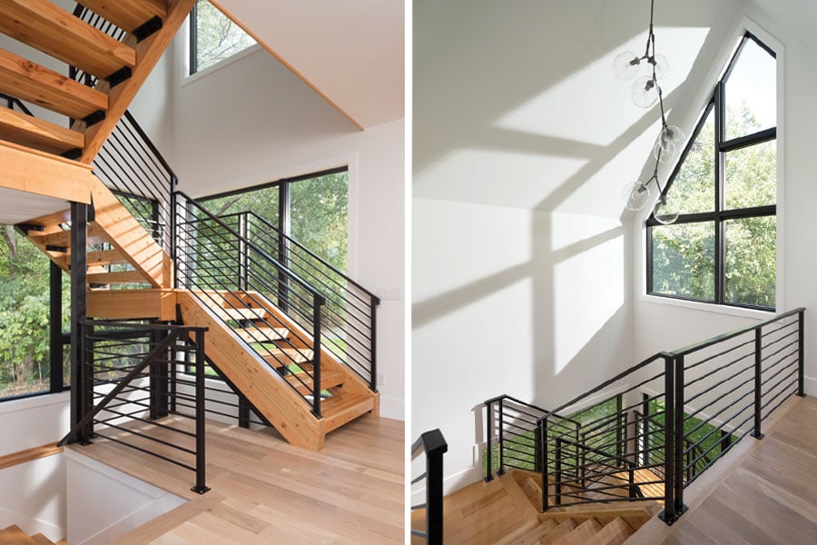 A stair tower in a contemporary home features open-tread stairs with an industrial-style black railing and specialty shaped windows with black frames.