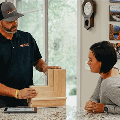 A contractor shows a customer a window corner section.