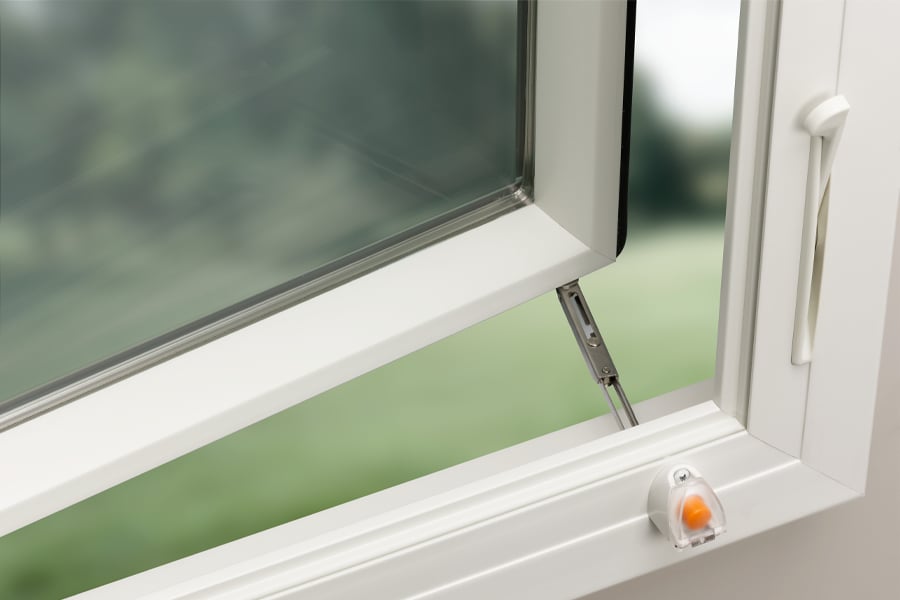 A white casement window with a window opening control device that keeps it from opening more than 4 inches.