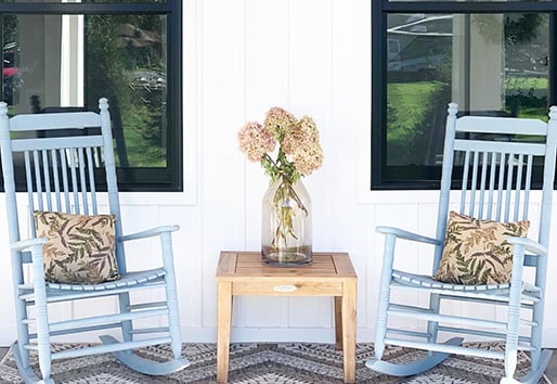 blue rocking chairs in front of a white home with Andersen windows