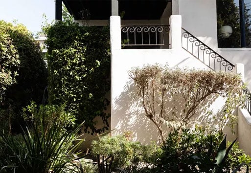 exterior of white Spanish style home, view of the front entrance stairway with Andersen black framed windows